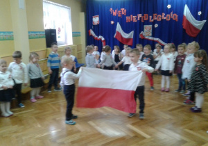 Dwóch chłopców trzyma rozwiniętą flagę Polski